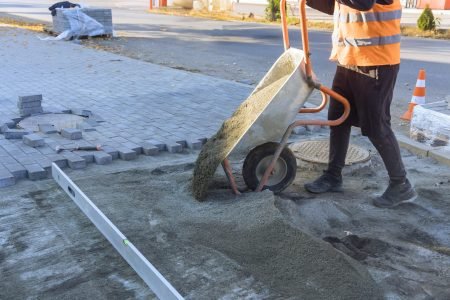 Pouring sand from wheelbarrow onto footpath in preparation for laying of decorative stones